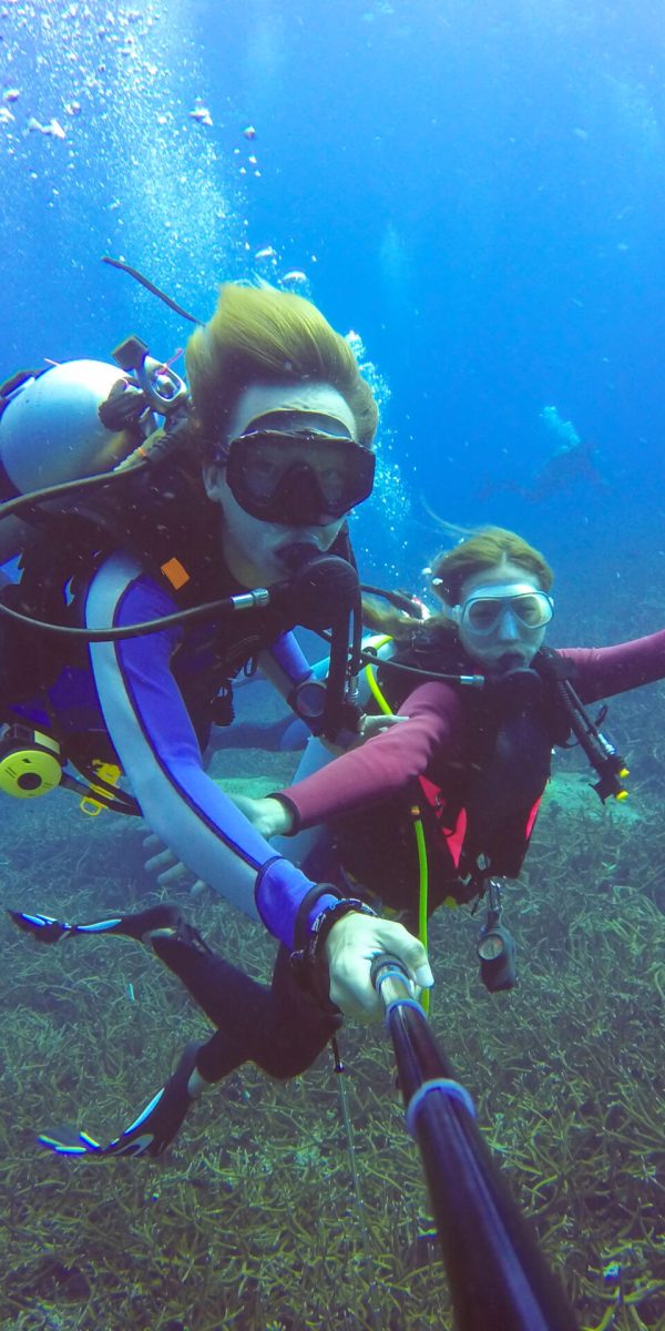 Underwater scuba diving selfie shot with selfie stick. Deep blue sea. Wide angle shot.